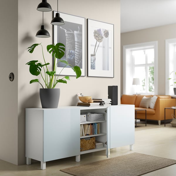 Weißes Sideboard mit verstellbaren Regalen, in dem Bücher, ein Lautsprecher und eine Pflanze Platz finden. Bietet Stau- und Ausstellungsfläche.