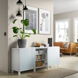 Weißes Sideboard mit verstellbaren Regalen, in dem Bücher, ein Lautsprecher und eine Pflanze Platz finden. Bietet Stau- und Ausstellungsfläche.