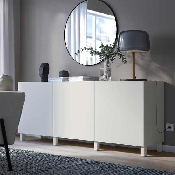 Weißes BESTÅ Sideboard mit Spiegel, Lampe, Vase und Büchern.