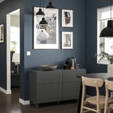 Dunkelgrauer BESTÅ-Schrank, weißes Dekor, Kunstwerk, Holzstühle, schwarze Lichter, marineblaue Wände.