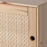 Nahaufnahme eines Holzschranks mit geflochtener Korbfront, die hochwertige Verarbeitung zeigt.