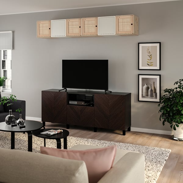 Modernes Wohnzimmer mit BESTÅ TV-Möbel und Korbtüren, dunkelbraun, vor grauer Wand, Kunst, Pflanze, schwarzem Couchtisch, beigem Sofa.
