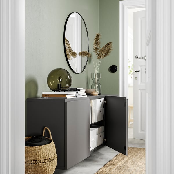 Moderner Eingangsbereich mit schwarzem BESTÅ-Schrank, Spiegel, Lampe und Vase.