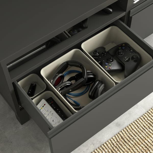 Schwarze BESTÅ TV-Bank mit organisierter Schublade: Gaming-Controller und Kopfhörer.