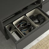Schwarze BESTÅ TV-Bank mit organisierter Schublade: Gaming-Controller und Kopfhörer.