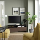 Modernes Wohnzimmer mit Fernseher auf einem Holzständer mit zwei Schubladen für Kabelmanagement und Aufbewahrung.