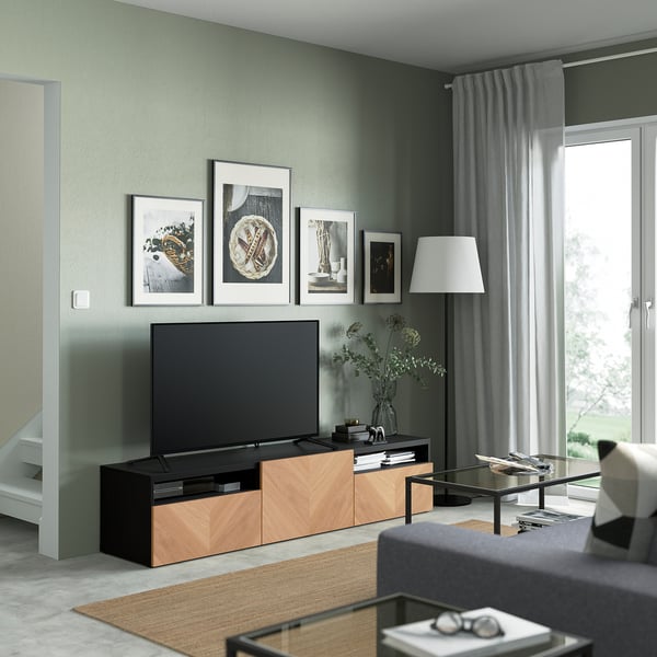 Grünes Wohnzimmer mit BESTÅ-TV-Bank, Flachbildfernseher, Kunst, grauem Sofa, Couchtisch, Pflanze.
