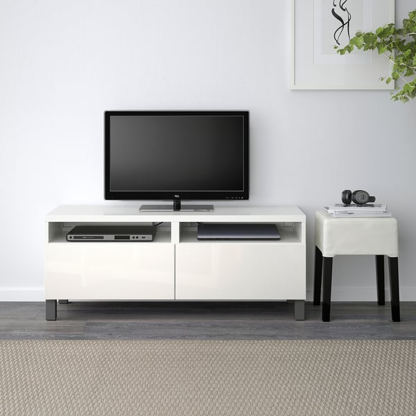 Weiße BESTÅ TV-Bank mit Flachbildschirm, 2 Schubladen, DVD-Player, Kopfhörer, Buch auf kleinem Tisch, minimalistisches Zimmer.