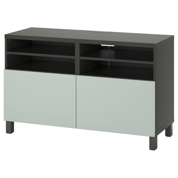 Eine IKEA BESTÅ TV-Bank in Grün mit hellgrauen Türen, offenen Regalen und verstellbaren Fächern mit Kabelmanagement.