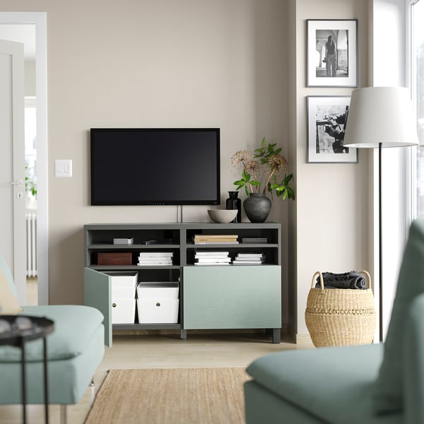 Modernes Wohnzimmer mit BESTÅ-TV-Ständer in Blaugrün mit Flachbildfernseher, Büchern, Vasen und gerahmten Bildern an der Wand.