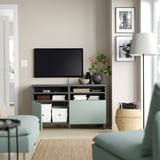 Modernes Wohnzimmer mit BESTÅ-TV-Ständer in Blaugrün mit Flachbildfernseher, Büchern, Vasen und gerahmten Bildern an der Wand.