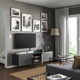 Modernes Wohnzimmer mit schwarzem BESTÅ-TV mit einem Flachbild-TV, dekorativen Rahmen und einem Couchtisch aus Glas.