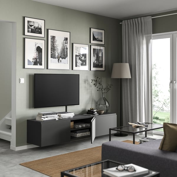 Modernes Wohnzimmer mit grauer BESTÅ-TV-Bank, elegantem schwarzem Fernseher und weiß gerahmten Fotos an olivfarbener Wand.