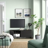 Modernes Wohnzimmer mit BESTÅ-TV-Ständer, grünen Wänden, Bergfotos, Sofa, Pflanze und Dekor.