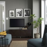Modernes Wohnzimmer mit grauen Wänden, BESTÅ-TV-Konsole, Fotos, grüner Pflanze, blauen Stühlen mit gelber Decke.