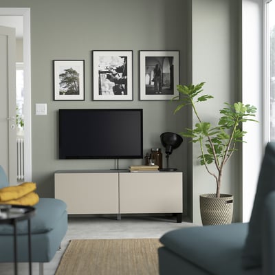 Modernes Wohnzimmer mit grauen Wänden, BESTÅ TV-Bank, Flachbildfernseher, Lampe, Bücher, Pflanze, blaues Sofa, gelbes Kissen, Fotos - gemütlich und stilvoll.