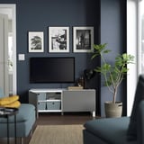 Modernes Wohnzimmer mit Fernseher auf BESTÅ-Bank, dunkelblaue Wand.