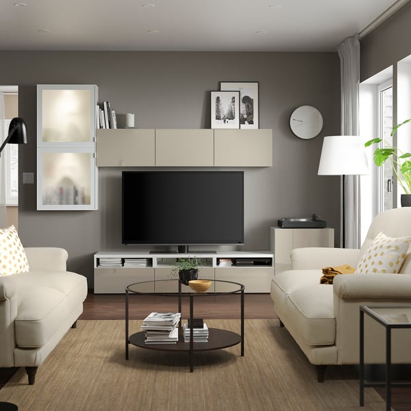 Modernes Wohnzimmer mit großem Fernseher und weißen Sofas.