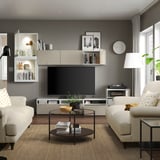 Modernes Wohnzimmer mit hellen Möbeln, darunter Sofas, ein Couchtisch und ein TV-Ständer mit verstellbaren Regalen und Kabelmanagement.