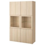 Ein BESTÅ-Schrank aus hellem Holz. Es handelt sich um vier Türabschnitte mit zwei Glastüren für die Ausstellung und zwei Massivholztüren für die Lagerung.