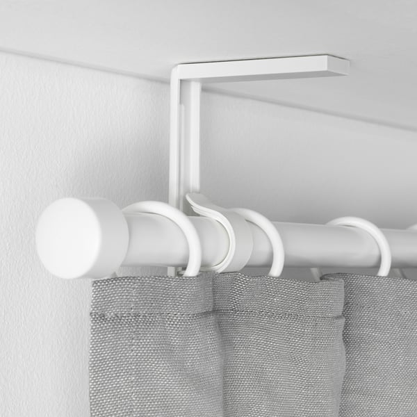 Weißer, verstellbarer Gardinenstangenhalter, der an der Wand montiert ist und hellgraue Vorhänge trägt.