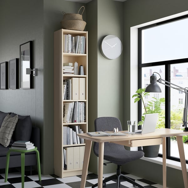 Modernes Homeoffice mit BILLY Bücherregal, Stuhl, Laptop, Lampe, Hocker und Kunstwerken.