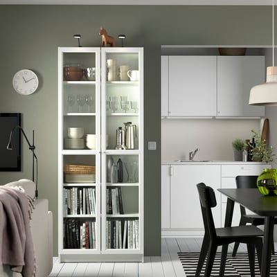 Modernes Wohnzimmer mit BILLY Bücherregal, grüner Wand, schwarzen Stühlen.