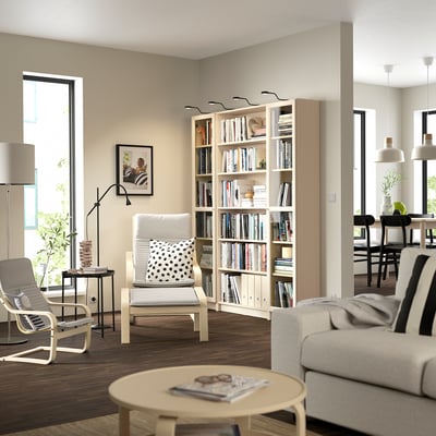 Modernes Wohnzimmer mit BILLY Bücherregal, Stühlen, Couch, großen Fenstern, ordentlicher Einrichtung.