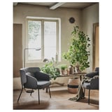 Gemütliches Zimmer mit grauem BINGSTA-Sessel, großem Fenster, Pflanzen, Naturholzboden, rustikaler Einrichtung.