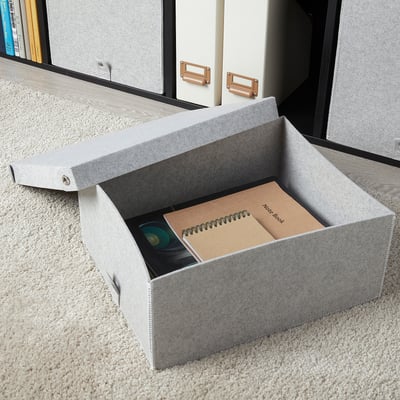 Graue BLÄDDRA Aufbewahrungsbox aus Filz im Regal für Notebook und CD-Hülle, kleiner als Bücher.