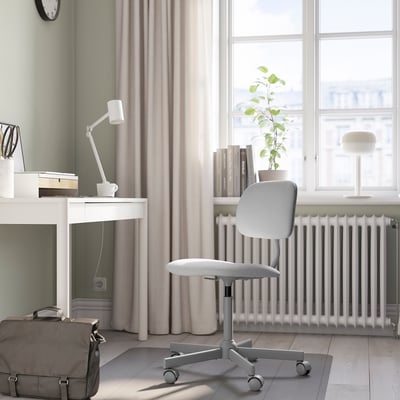 Minimalistische Einrichtung des Home-Office: weißer Schreibtisch, grauer Stuhl, großes Fenster, Pflanze und Lampe.