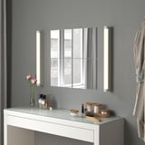 Fazit: ein modernes Badezimmer, das Spiegeltrio BLODLÖNN in Silber, flankiert von beleuchteten Wandlampen, auf einem weißen Waschtisch mit Toilettenartikeln und rosa Rosen.