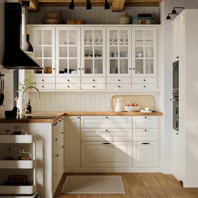 Eine cremefarbene Schranktür mit abgeschrägter Platte, glatt lackierter Oberfläche und traditionellem Design. Es ist rechteckig mit einem einfachen Rahmen.