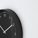 Schwarze runde Wanduhr mit weißen Zeigern und Zahlen, stilvoll und leise, kein Ticken.