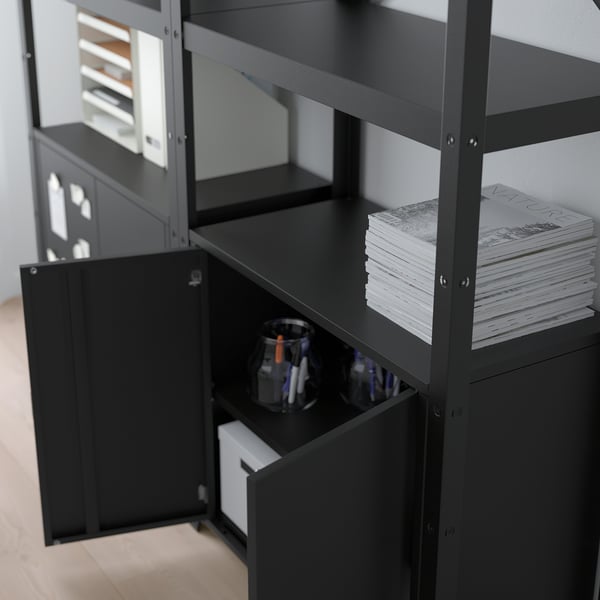 Aufbewahrungsschrank aus schwarzem Metall mit offenen Regalen, in dem Papierstapel und Büromaterial aufbewahrt werden.