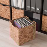 Aufbewahrungsbox aus geflochtenem Bambus, gefüllt mit Schallplatten vor Regalen.