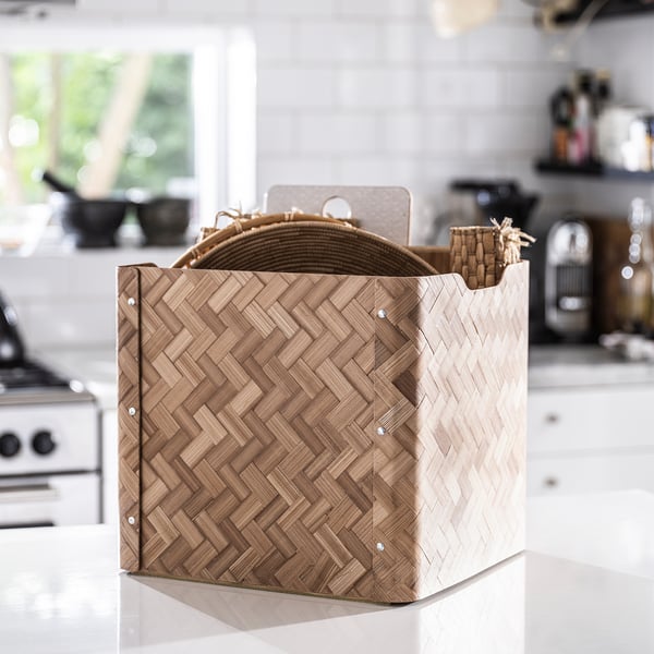 BULLIG Aufbewahrungsbox aus Bambus mit gewebtem Design, naturbrauner Farbe, quadratischer Form, auf der Arbeitsplatte.