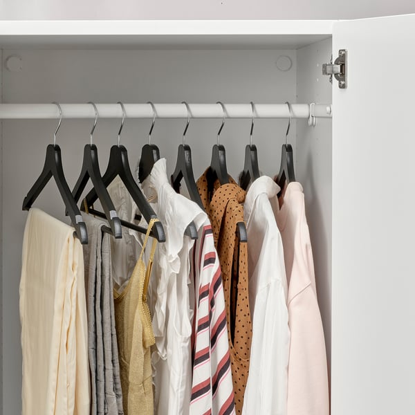 Ein Schrank mit Kleiderbügeln auf Kleiderbügeln, die hölzerne Kleiderbügel zeigen, die verhindern, dass die Kleidung herunterfällt.