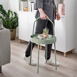 Person trägt grünen tragbaren Tisch mit Snacks und Getränken.