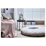 Modernes Schlafzimmer mit BURVIK Bett, grauer Steppdecke, großem Bodenkissen, kleinem runden Beistelltisch mit Griff, sonstiges Dekor.