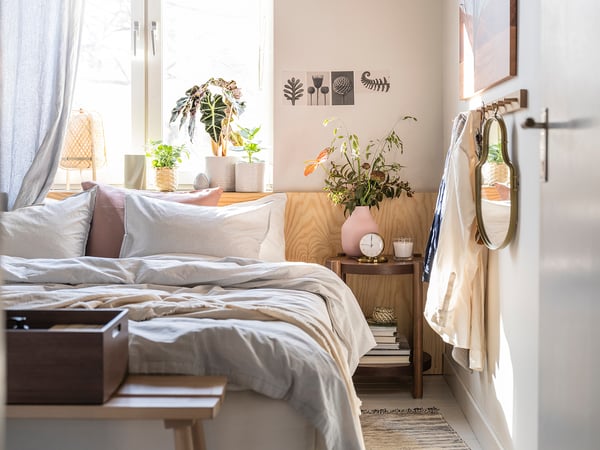 Gemütliches Schlafzimmer mit Pflanze, gestreiften Kissen, Holzmöbeln.