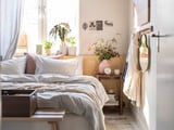Gemütliches Schlafzimmer mit Pflanze, gestreiften Kissen, Holzmöbeln.