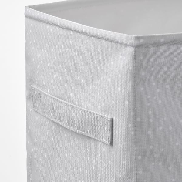Nahaufnahme einer Aufbewahrungsbox aus Stoff mit Fronttasche, weiß mit kleinen Punkten.