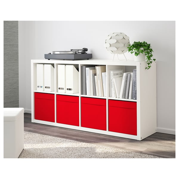 Ein weißes Bücherregal mit roten Schubladen, in dem Schallplatten, Bücher und eine Pflanze aufbewahrt werden.