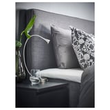 Modernes Bett mit Kopfteil, Kissen, Beistelltisch mit Pflanze.