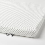 Eine Nahaufnahme einer weißen Matratze von IKEA. Die Textur erscheint weich und atmungsaktiv und ist auf Komfort ausgelegt.