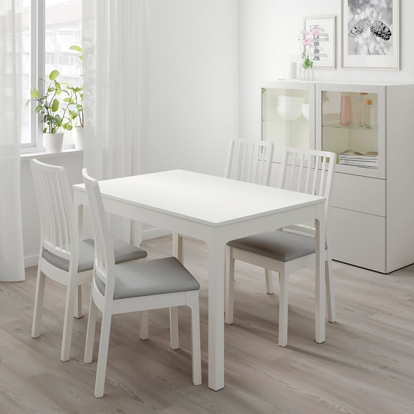 Kleine weiße EKEDALEN Essgarnitur mit zwei Stühlen und einem kompakten Tisch in der Nähe eines Fensters.