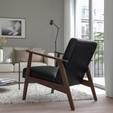 Modernes Wohnzimmer mit schwarzem EKENÄSET-Sessel, weißem Sofa, Couchtisch und großem Fenster.