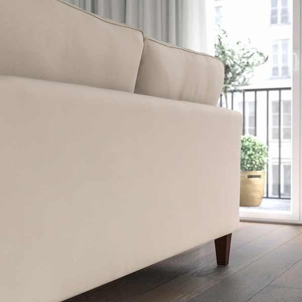 Beigefarbenes EKHOLMA Sofa in der Nähe des Fensters mit Topfpflanze, das Komfort und einen Hauch von Eleganz bietet.