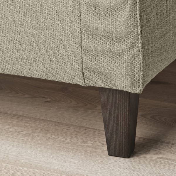 Nahaufnahme eines stilvollen Sofabeins. Robustes, dunkles Holzfinish. Strukturierter, neutraler Stoff.